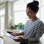 Woman using digital tablet in kitchen