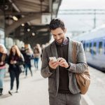 Businessman using mobile phone at train station